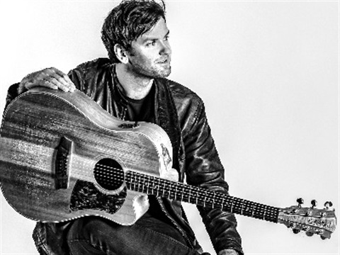 Black & white image of artist Daniel Champagne with his guitar