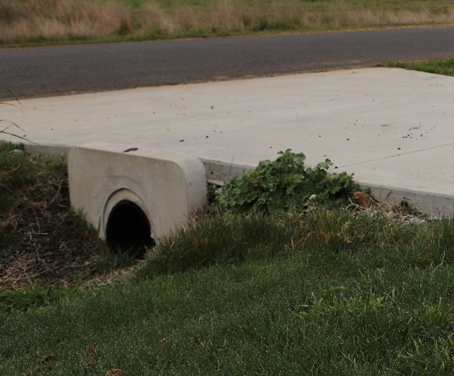 A sealed driveway crossing over a concrete pipe.